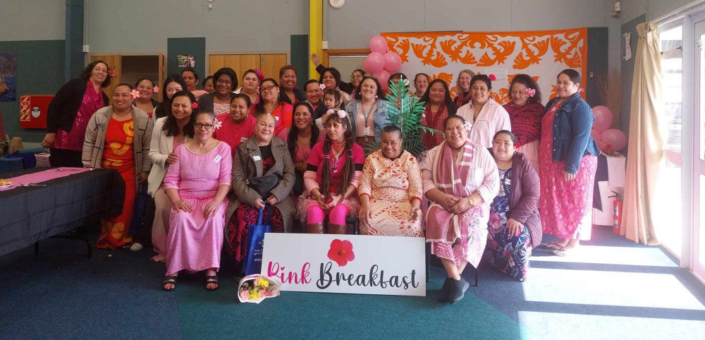 Group of attendees sitting behind a ‘Pink Breakfast’ poster